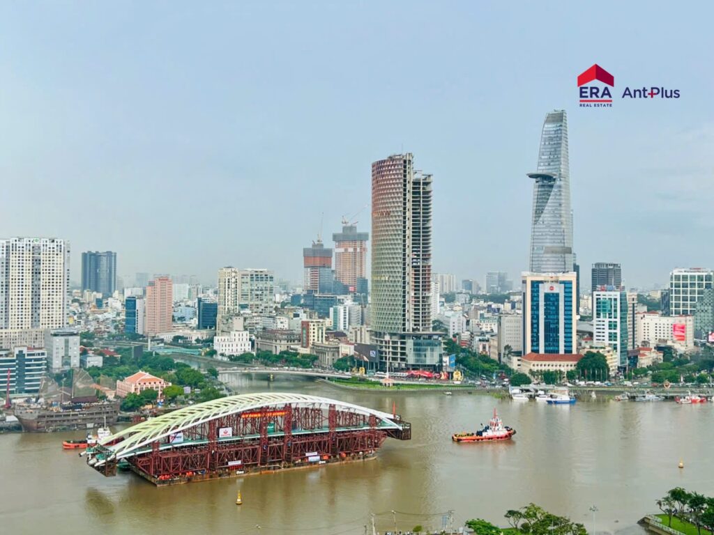 Nhịp chính cầu đi bộ Thủ Thiêm hình lá dừa nước được lai dắt trên sông Sài Gòn, phía sau là tòa Bitexco và trung tâm TP.HCM